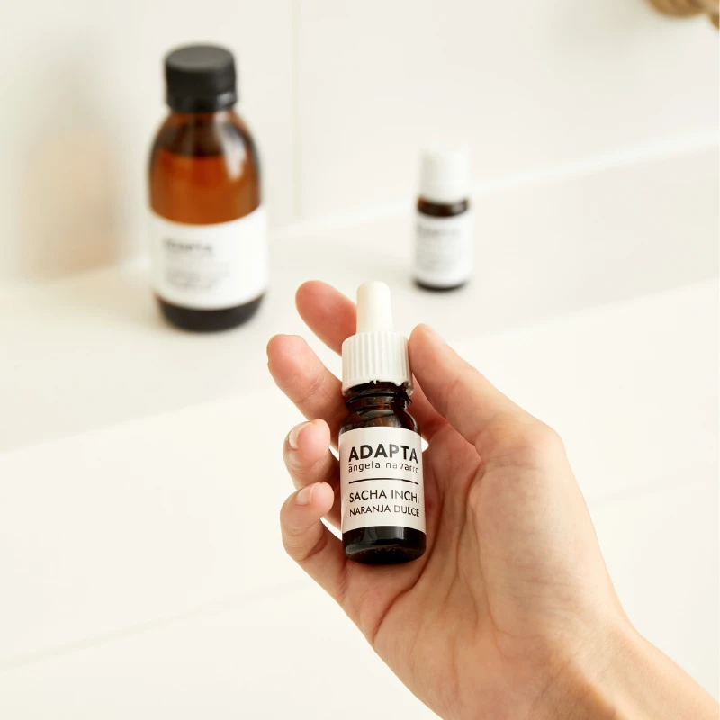 Aceite de Sacha Inchi en frasco de cristal ámbar sostenido en la mano, de ADAPTA Cosmetics